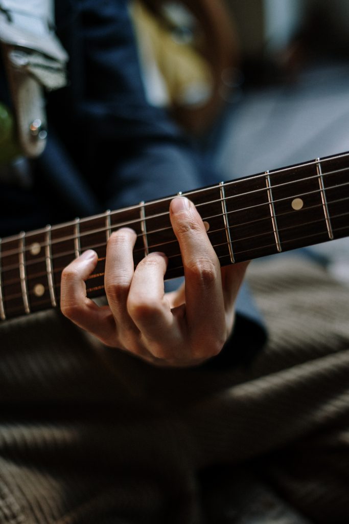 Guitar fret board, with a student holding a chord position to show a music teacher