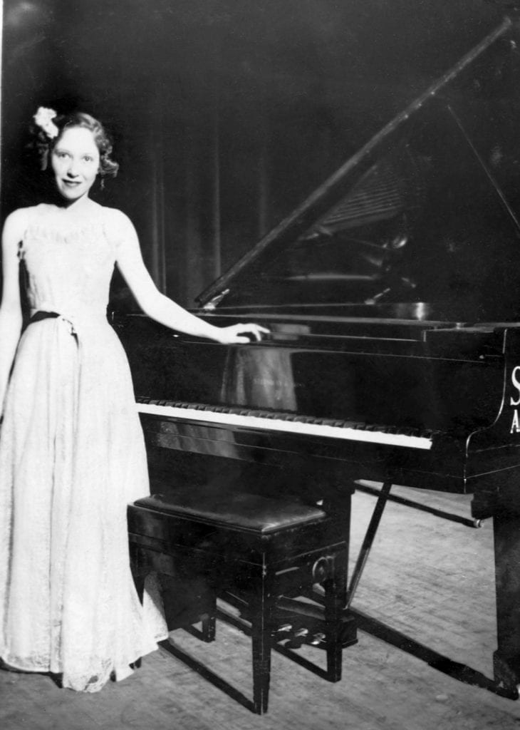 Image of a young Dame Fanny Waterman by a piano