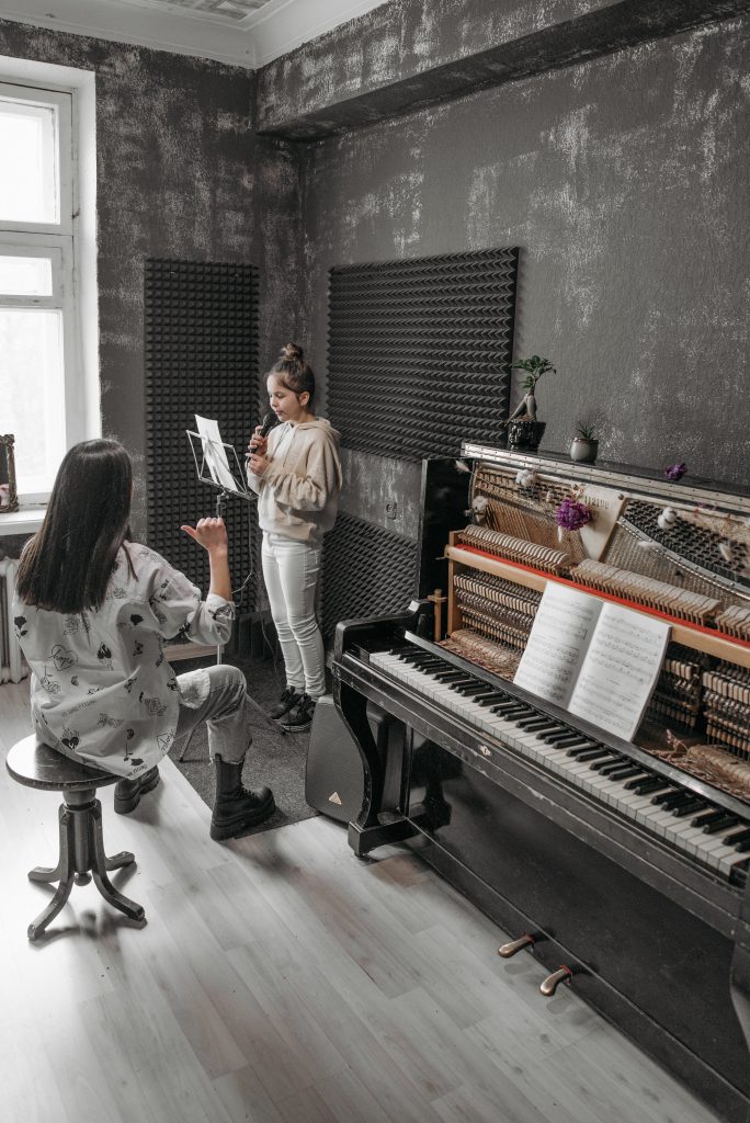 Girl learning to sing with teacher in front of piano